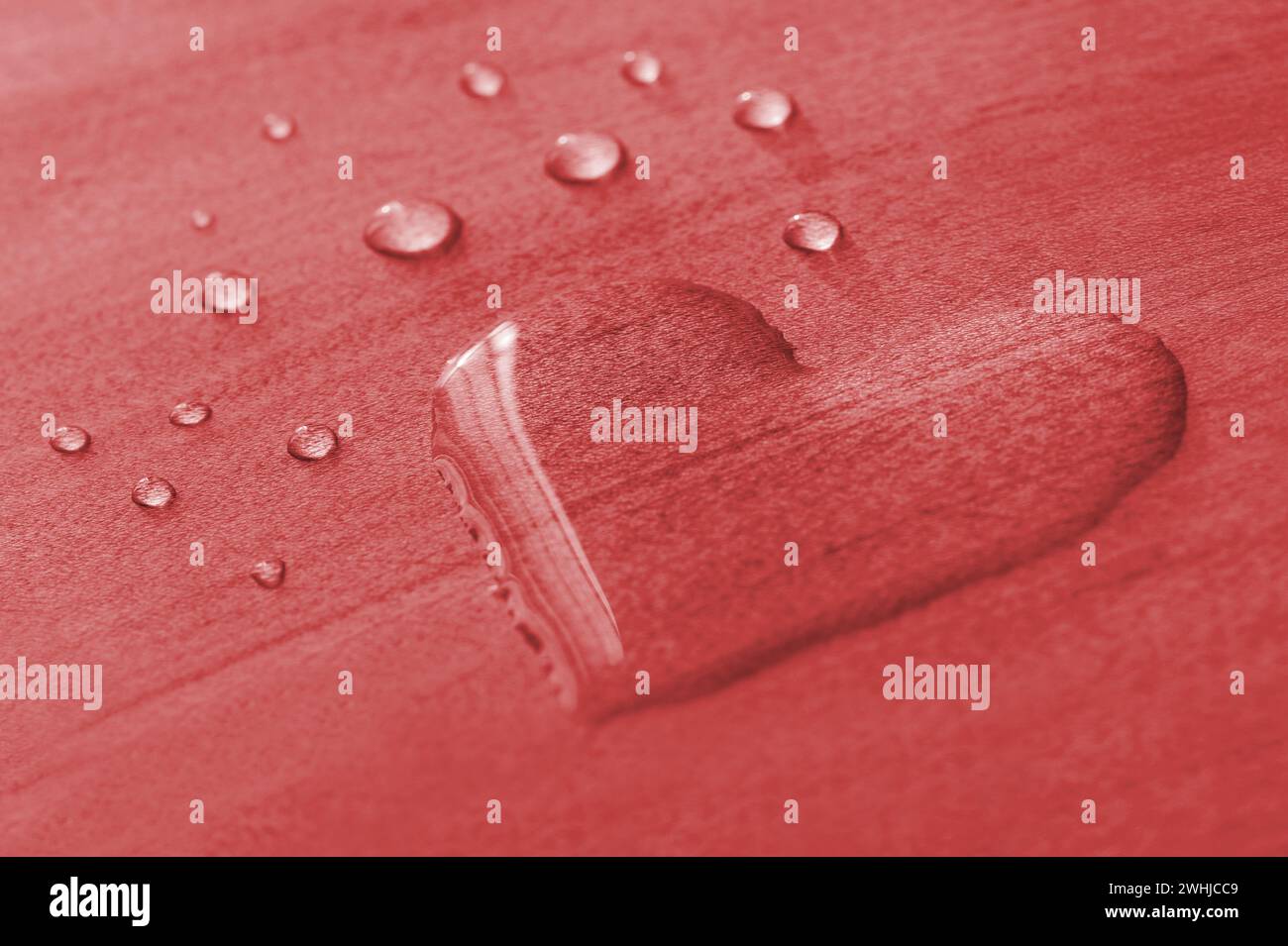 Wassertropfen in Form von Herz auf einem roten Holzhintergrund, Valentinstag Konzept. Wasser In Herzform Stockfoto