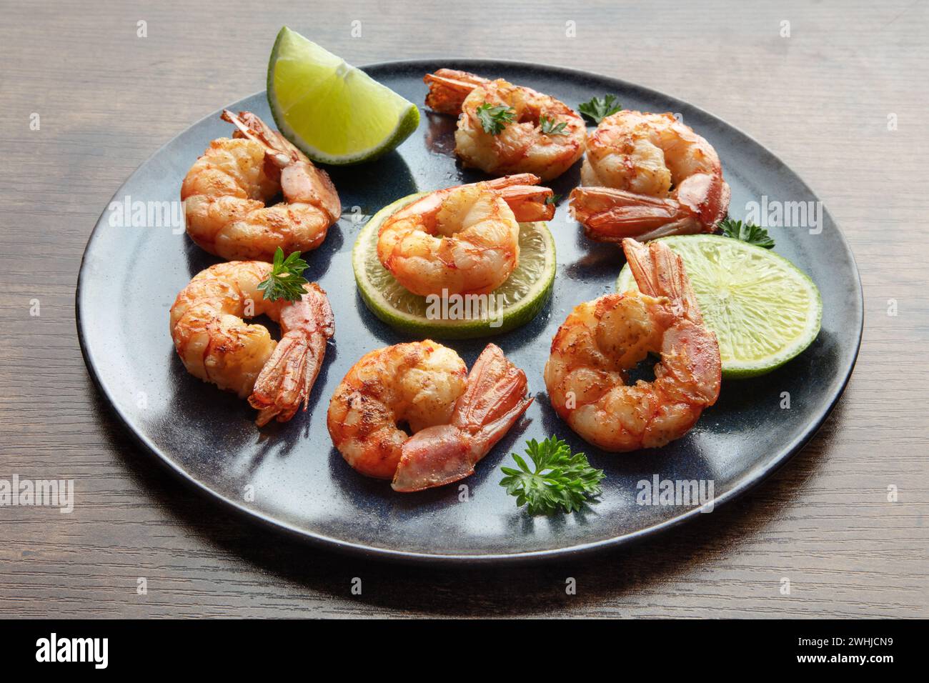 Garnelen mit Limetten und Petersilie. Gegrillte Garnelen auf einem rustikalen Tisch Stockfoto