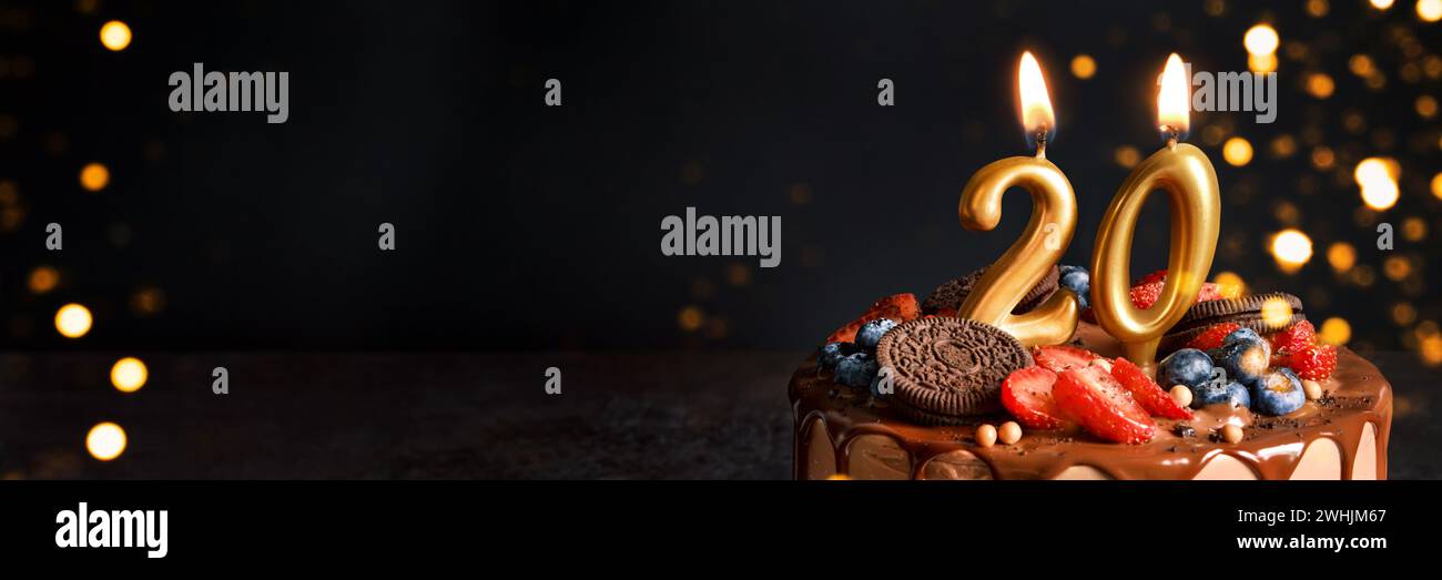 Banner mit Schokolade Geburtstagskuchen mit Beeren, Keksen und Zahl zwanzig goldene Kerzen auf schwarzem Hintergrund, Kopierraum Stockfoto