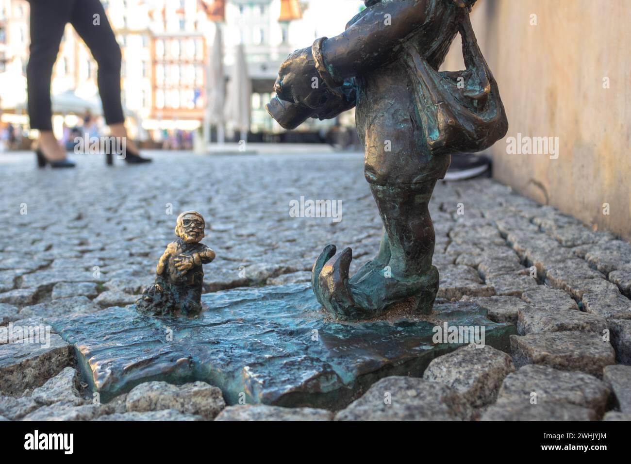 Der Breslauer Zwerg Adoratorek wird von Zwerg Troszka auf dem Breslauer Hauptplatz fotografiert, mit Menschen auf verschwommenem Hintergrund Stockfoto
