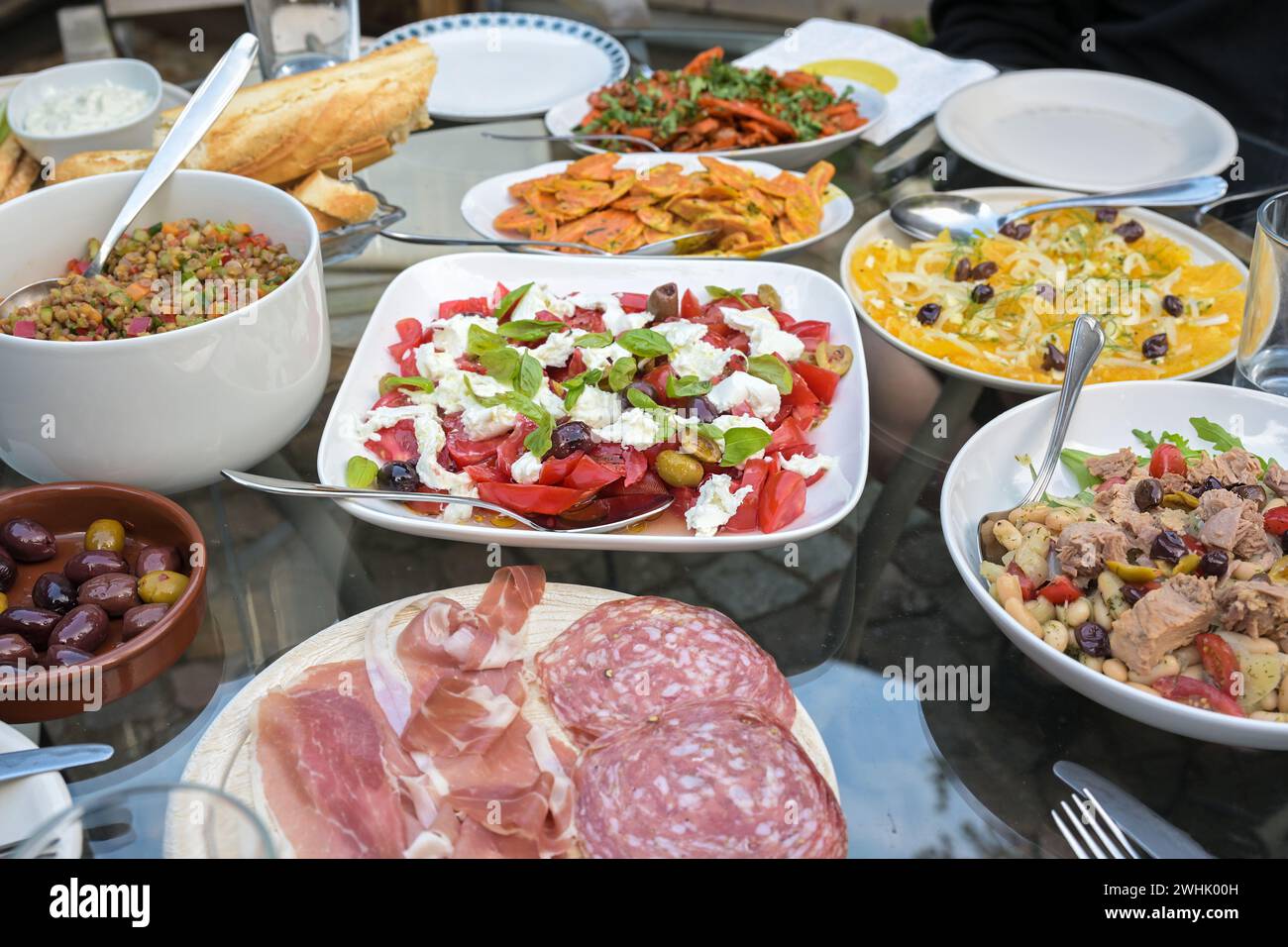 Sommer-Dinner-Tisch mit verschiedenen Salaten, Snacks und Brot für ein Partyessen mit Freunden oder Familie, ausgewählte Fokussierung Stockfoto
