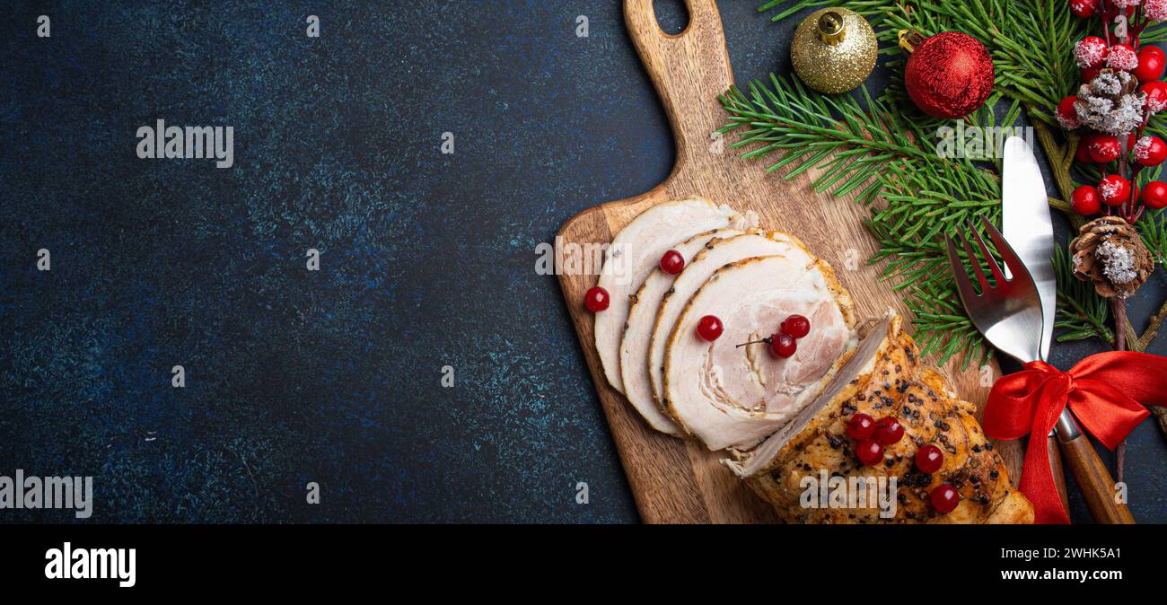 Weihnachtlich gebackener Schinken in Scheiben mit roten Beeren und festlichen Dekorationen Stockfoto Weihnachtlich gebackener Schinken in Scheiben mit roten Beeren und festlichen Dekorationen Stockfoto