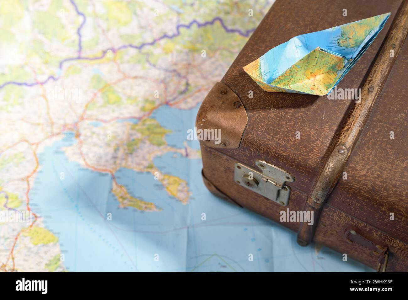 Gefaltetes Papierboot auf einem alten, alten Koffer auf einer Karte, Reise, Fernweh und Kreuzfahrtkonzept, Kopierraum, ausgewählter Fokus Stockfoto