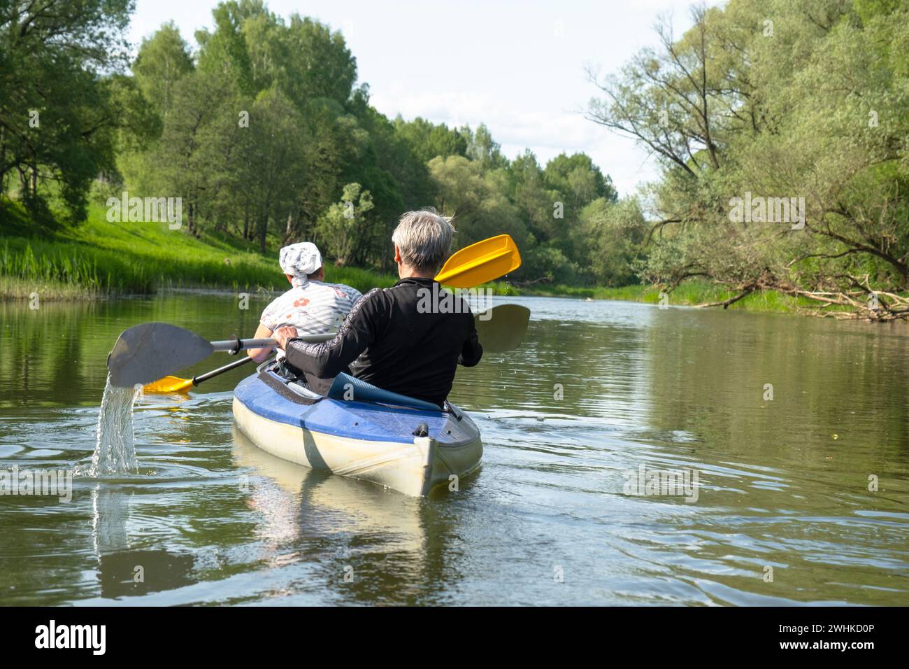 Familien-Kajakausflug für Seigneur und Senora. Ein älteres Ehepaar rudert ein Boot auf dem Fluss, eine Wasserwanderung, ein Sommerabenteuer Stockfoto