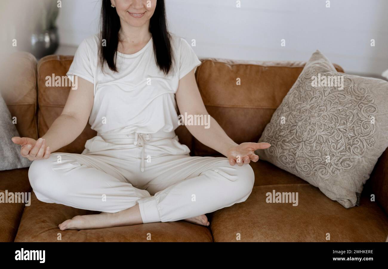 Frau, 40, macht Entspannungsübungen auf einer Couch Stockfoto