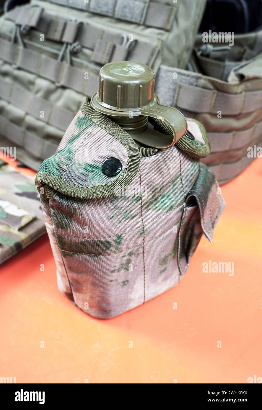 Wasserflasche aus militärischem Kunststoff mit Tarnschutzgewebe. Grüne Militärplastikflasche mit Schutzvorrichtung Stockfoto