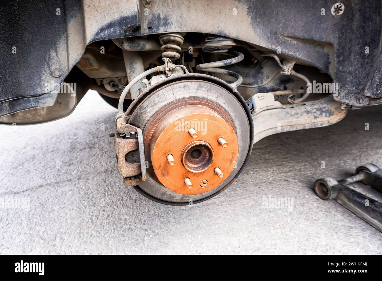 Eine alte rostige Bremsscheibe wird vor dem Einbau eines Fahrzeugrads mit Kupferfett geschmiert Stockfoto