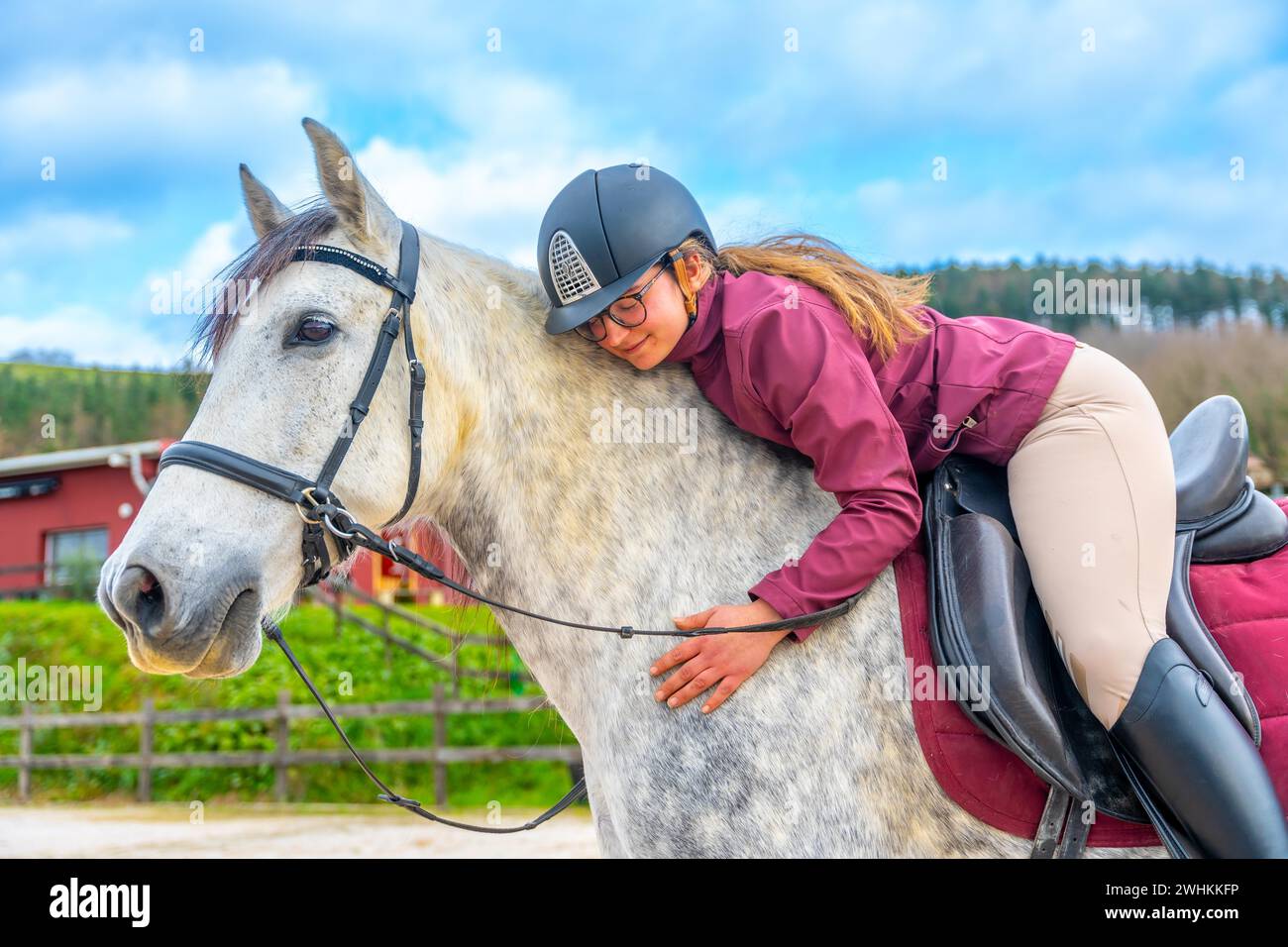 Eine Frau, die ein Pferd umarmen, während sie es in einem Reitzentrum reitet Stockfoto