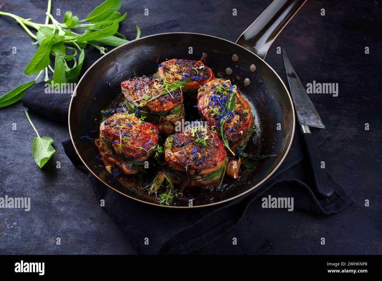 Traditionelle gebratene Kalbsfilet-Medaillons mit Speckbeschichtung und Salbeiblättern in Buttersauce, serviert als Nahaufnahme auf einem rustikalen Wrou Stockfoto