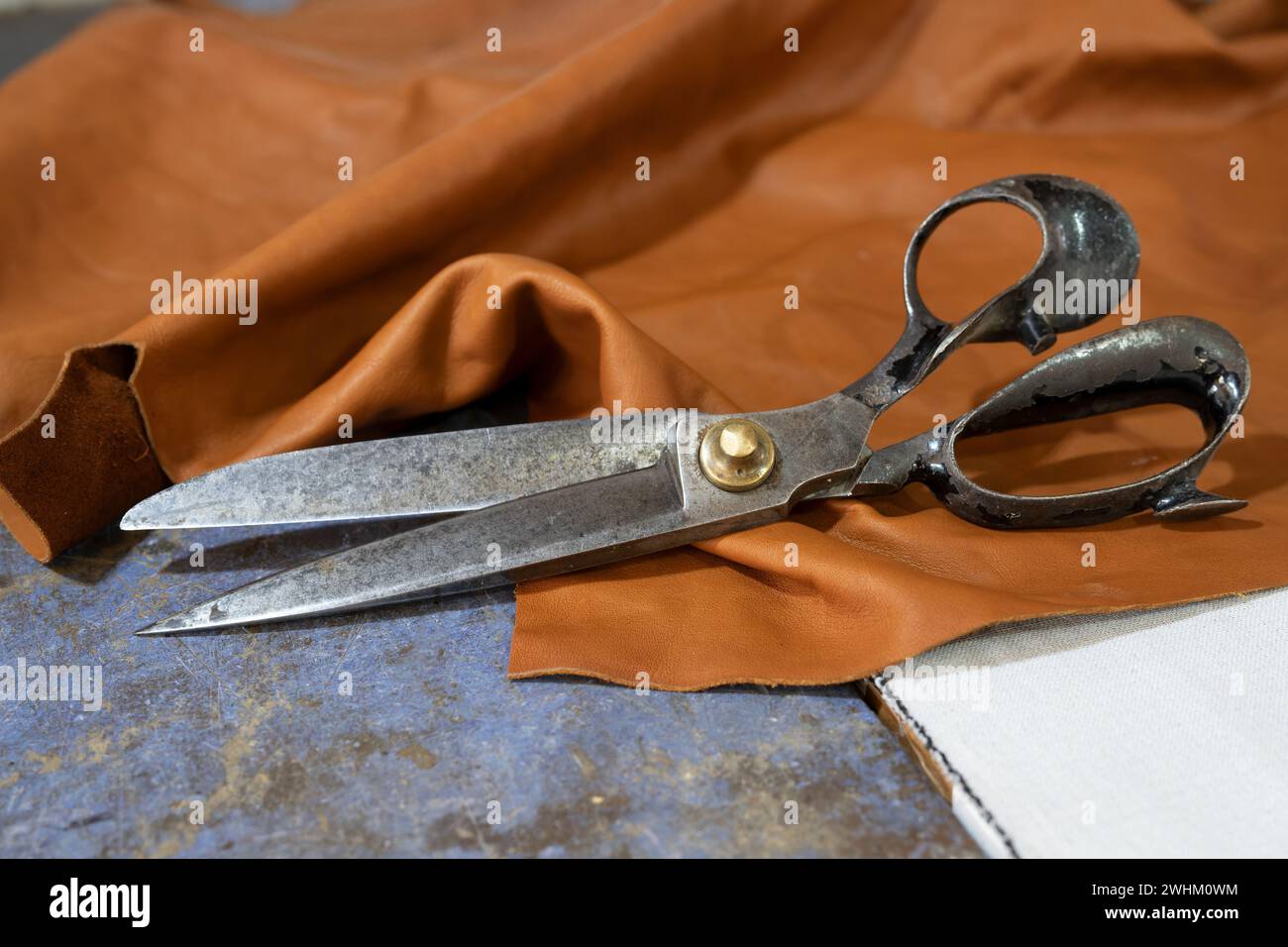 Große Vintage-Schere auf einem Stück Leder in einer Kunsthandwerkstatt, Kopierraum, ausgewählter Fokus Stockfoto