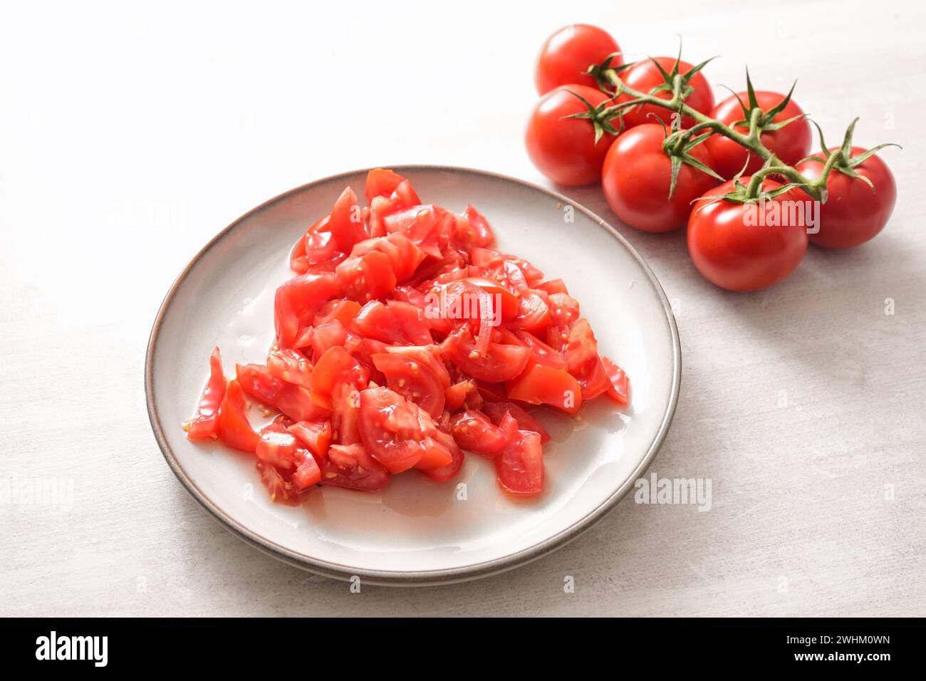 Tomaten, ganz und auf einem Teller gehackt, Zutat für verschiedene Gerichte, gesundes Kochkonzept, Kopierraum, ausgewählter Fokus Stockfoto
