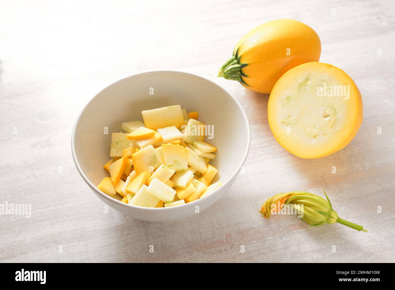 Gelbe Kugel Zucchini, ganz, in einer Schüssel gehackt und eine essbare Blume, Zutat für verschiedene Gemüsegerichte, vegetarische Küche Stockfoto
