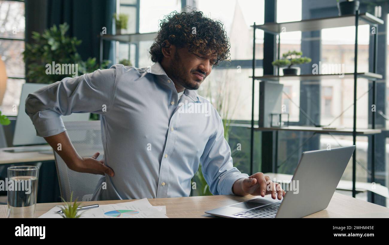 Müde krank arabischer hispanischer Geschäftsmann kranker Kerl leiden Rückenschmerzen Schmerzen im Rücken nach Laptop Computer Arbeit im Büro ungesunder Mann Geschäftsgeber Stockfoto