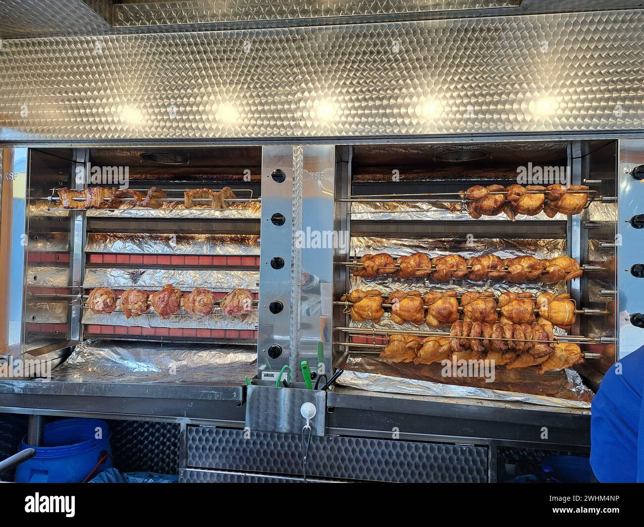 Gegrilltes Huhn und Schweinshaxe an einem mobilen Verkaufsstand Stockfoto