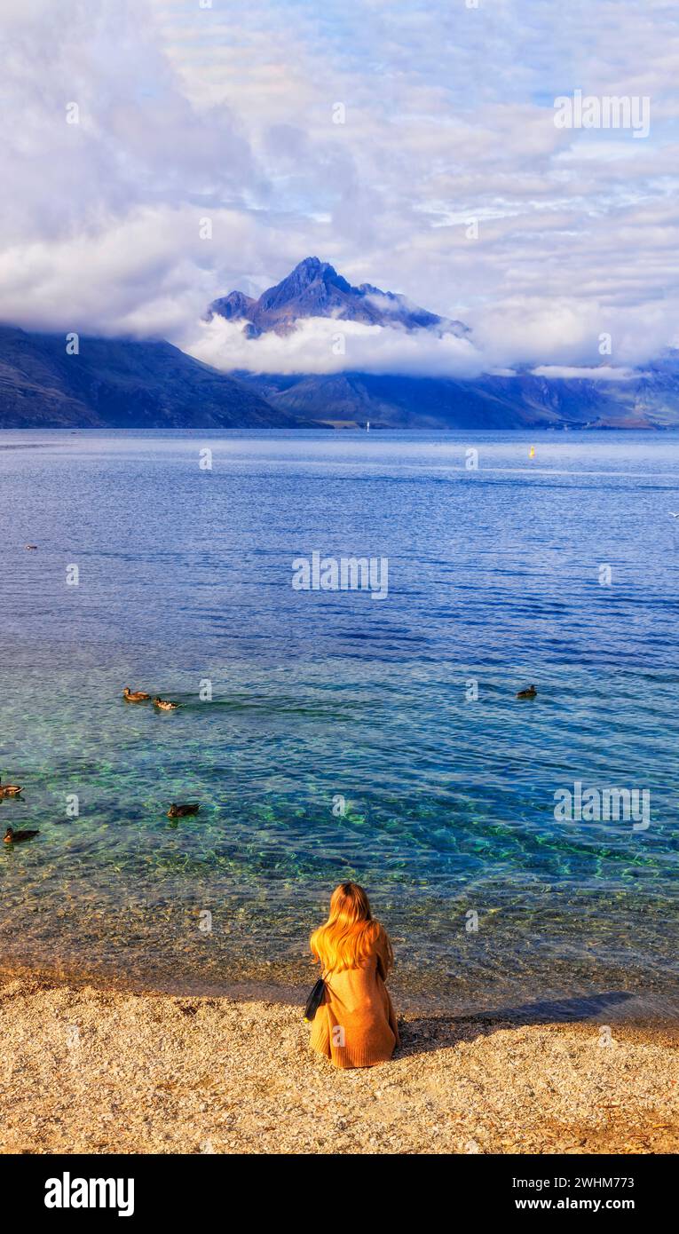 Einsame, nicht erkennbare Person am Strand von Queenstown mit Blick auf den See Wakatipu in Neuseeland. Stockfoto