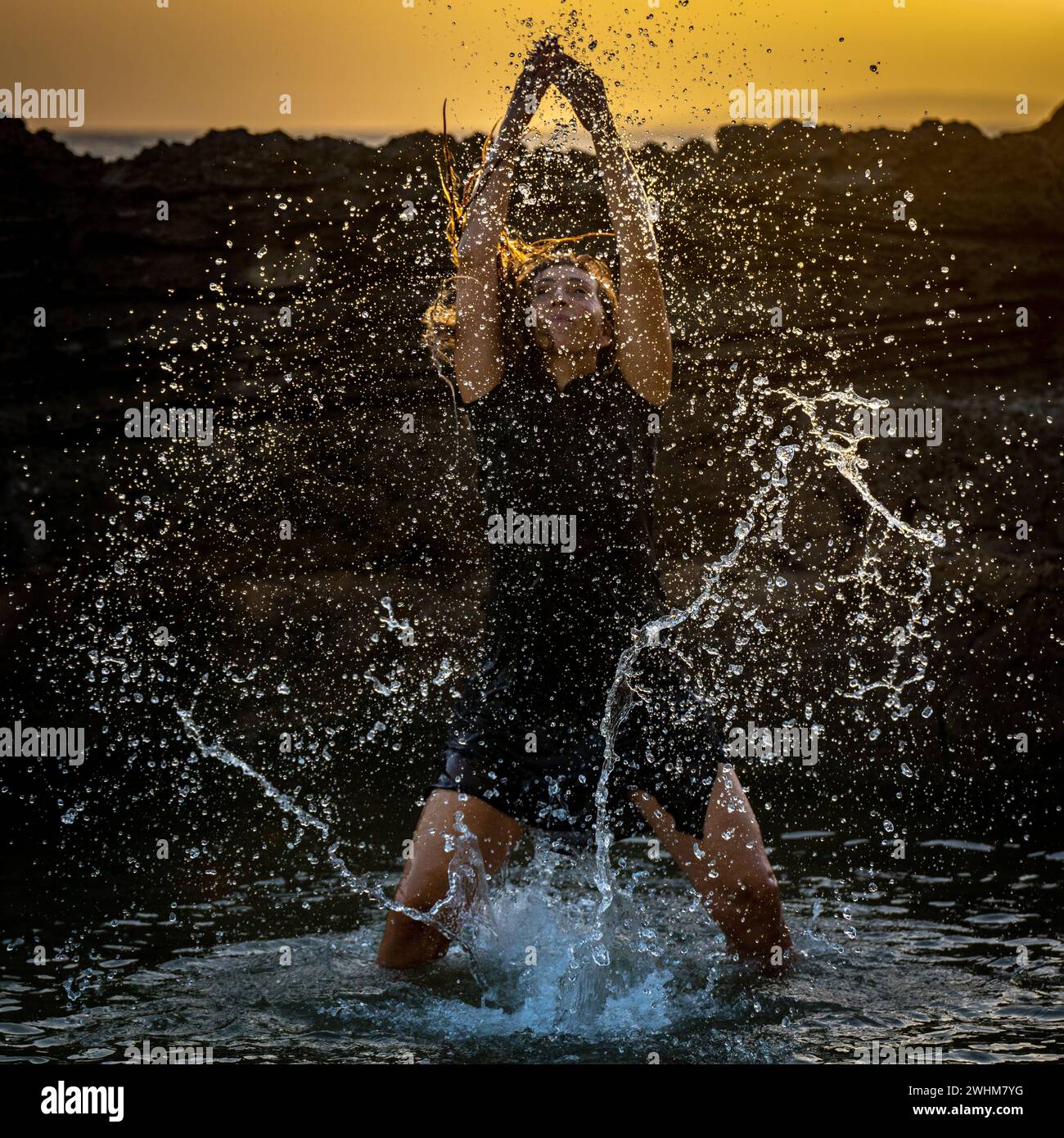 Eine Frau mittleren Alters, die tanzt und Wasser in die Luft wirft Stockfoto