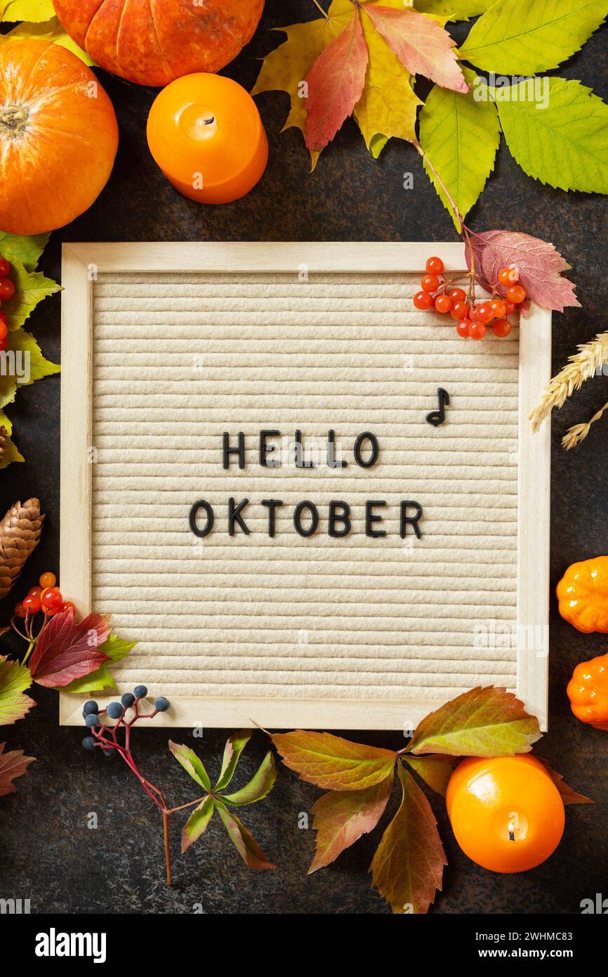 Herbsthintergrund mit Hello-Oktober-Briefen und Herbsttafel, Kürbissen und bunten Blättern. Gemütliche Herbststimmung. Herbstsee Stockfoto