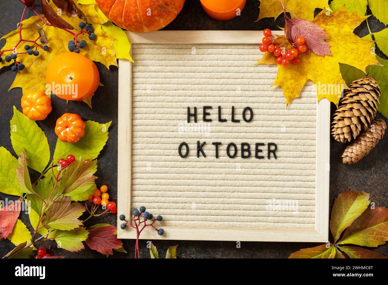 Herbsthintergrund mit Hello-Oktober-Briefen und Herbsttafel, Kürbissen und bunten Blättern. Gemütliche Herbststimmung. Herbstsee Stockfoto