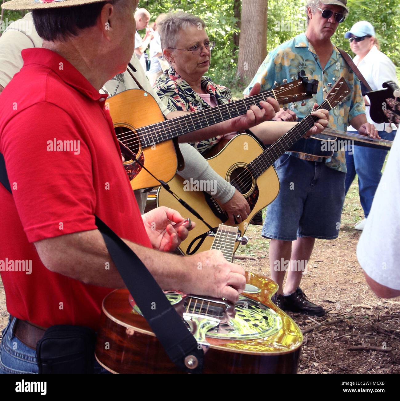 Musiker jammen in fließenden Gruppen unter Bäumen beim Old Fiddlers Picknick Stockfoto