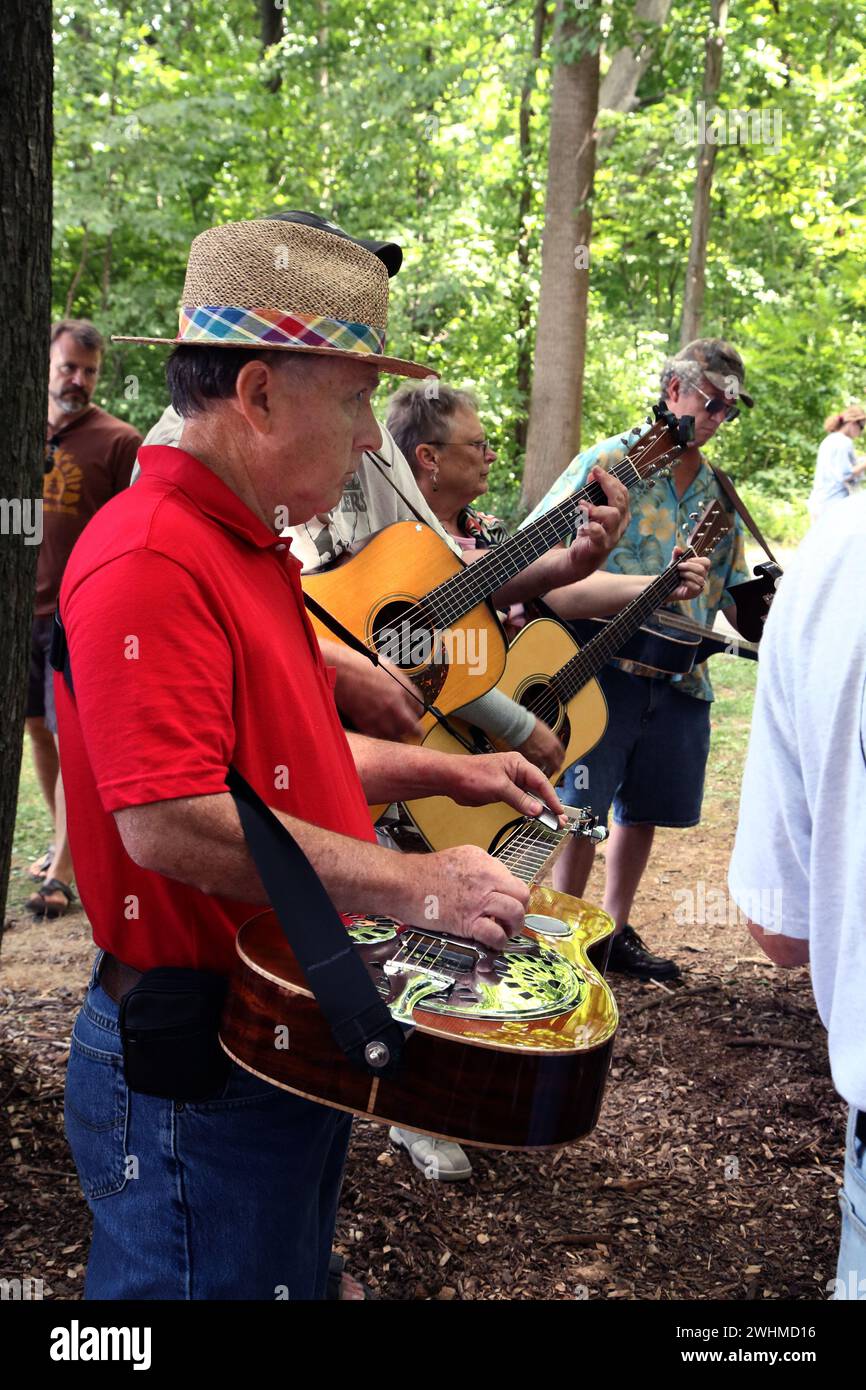 Musiker jammen in fließenden Gruppen unter Bäumen beim Old Fiddlers Picknick Stockfoto