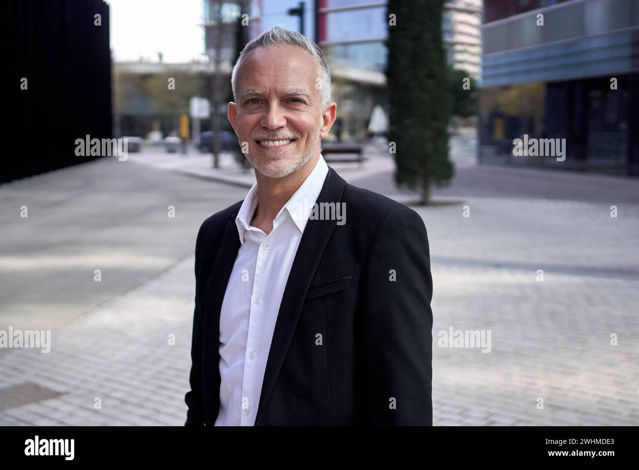 Porträt attraktiver reifer Geschäftsmann grizzled Executive sieht glücklich aus, wenn die Kamera im Freien steht. Stockfoto