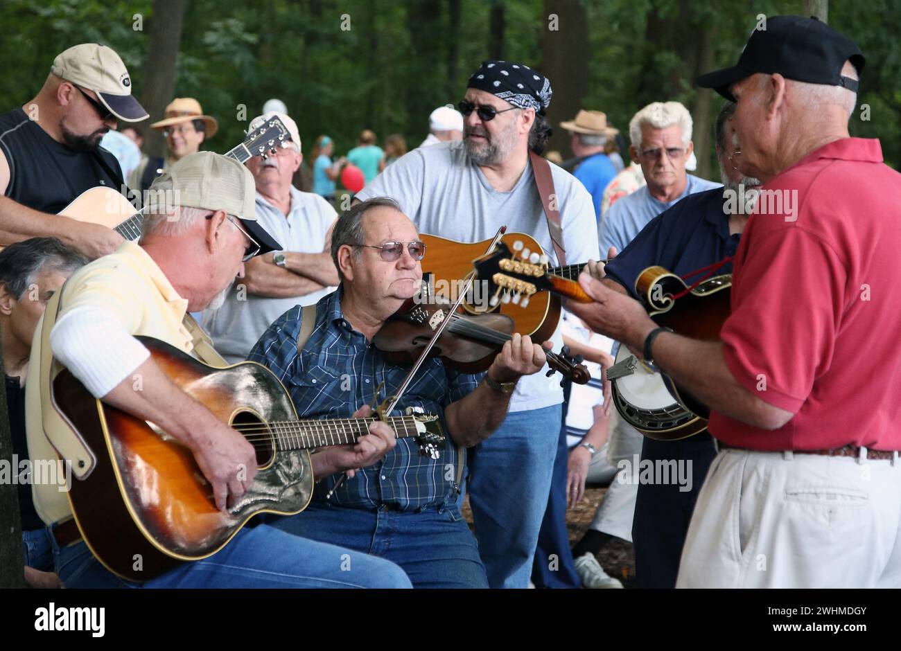 Musiker jammen in fließenden Gruppen unter Bäumen beim Old Fiddlers Picknick Stockfoto