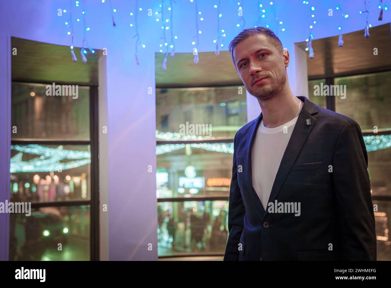 Mann in Blazer im festlichen Londoner Veranstaltungsort mit weihnachtlicher Einrichtung. Stockfoto