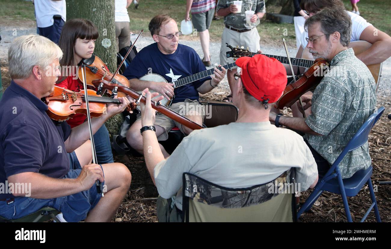 Musiker jammen in fließenden Gruppen unter Bäumen beim Old Fiddlers Picknick Stockfoto
