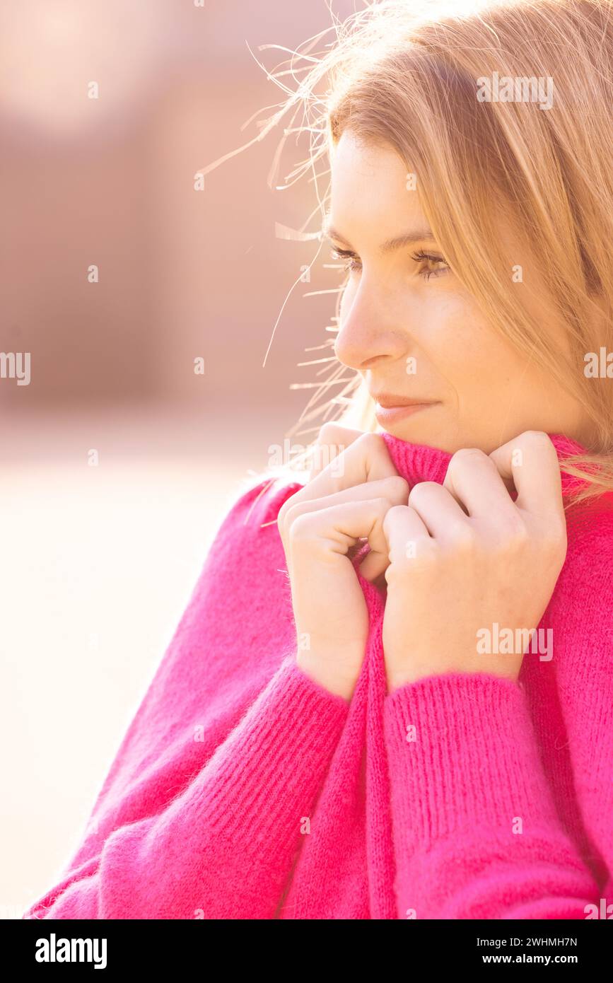 Gemütliches Millennial Retreat: Junge Frau, die Komfort in einem flauschigen rosafarbenen Pullover genießt Stockfoto