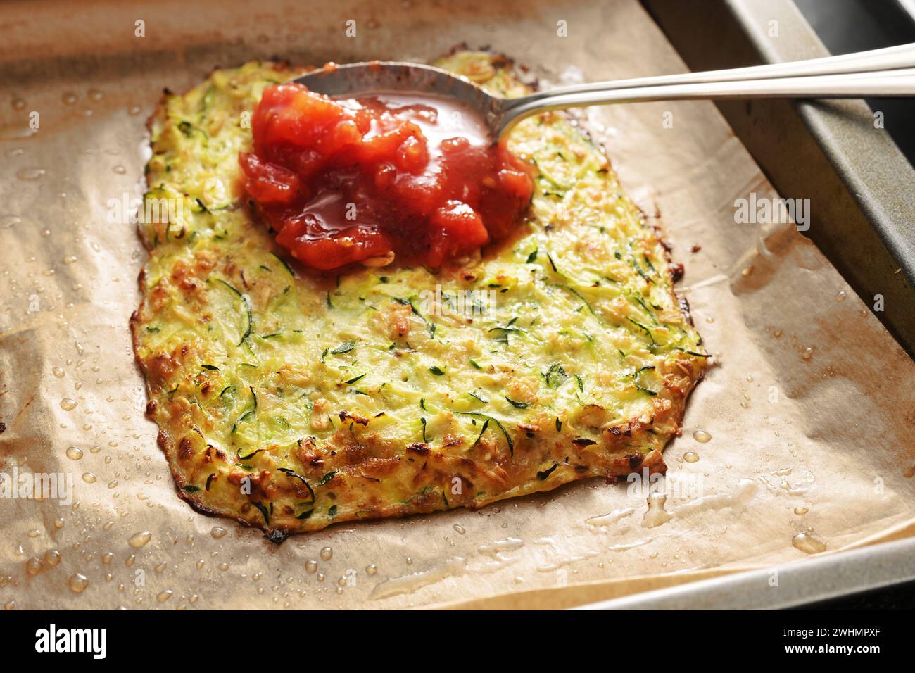 Tomatensauce wird auf einer gebackenen Kruste aus Zucchini und ... Tomatensauce wird auf einer gebackenen Kruste aus Zucchini und ...