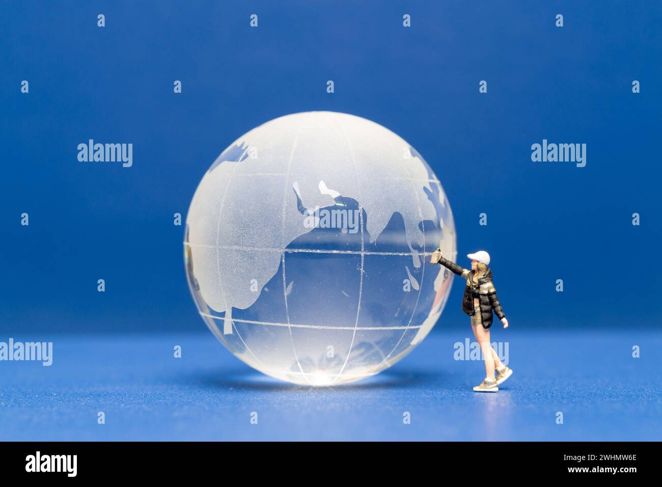 Miniaturmenschen Teenager, der Farbe Krytalkugel auf blauem Hintergrund sprüht Stockfoto