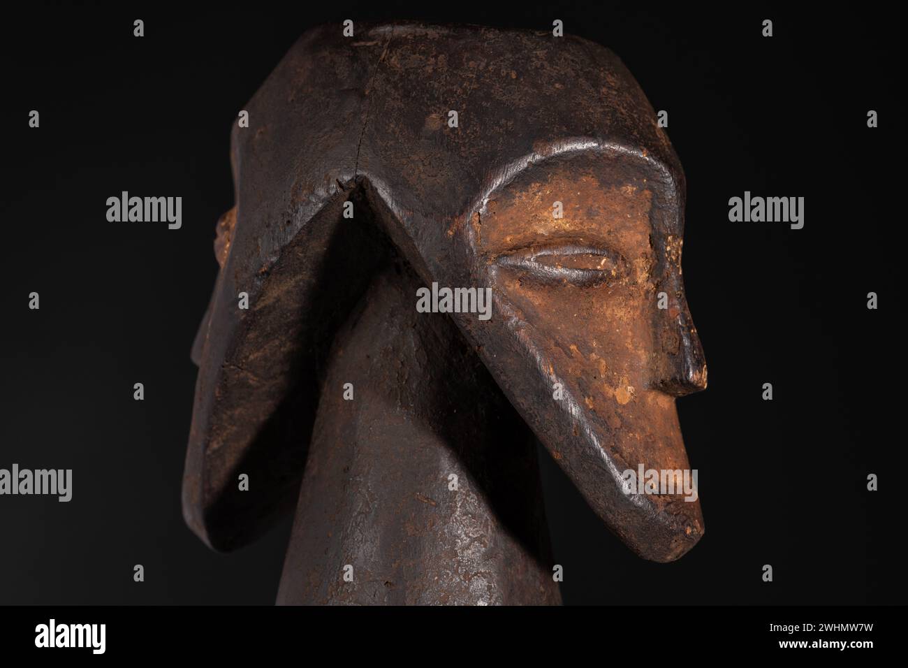 Nahaufnahme einer zweiköpfigen männlichen Figur, schöne schwarze Patina und Kaolin-Pigmente, isoliert auf Schwarz. Afrikanische Stammeskunst mit meisterhafter Handwerkskunst Stockfoto