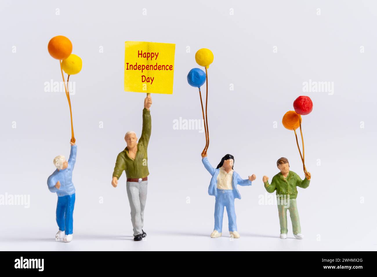 Miniatur-Leute halten Fahnen mit dem Wort Happy Independence Day Stockfoto