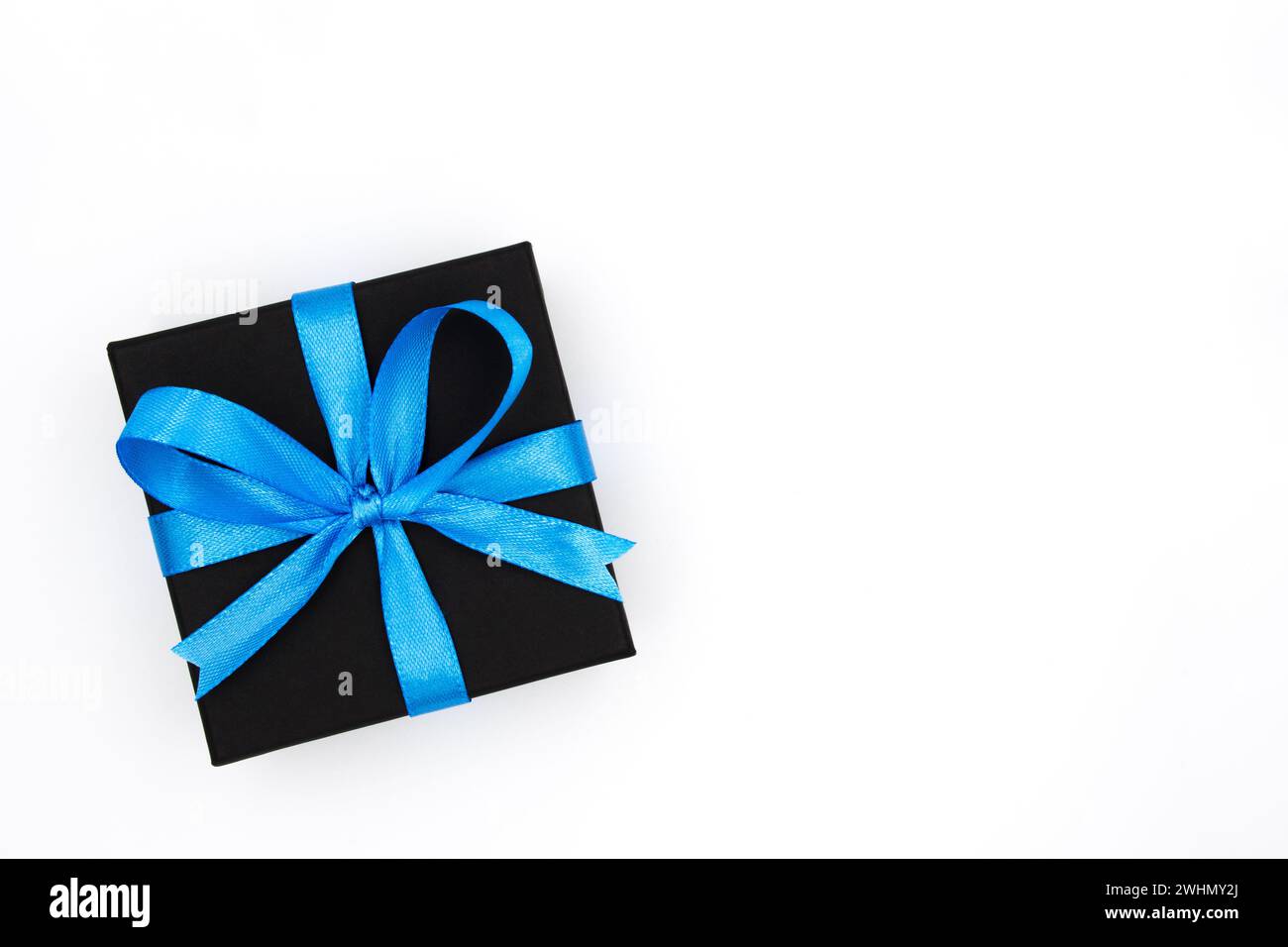 Geschenkbox aus schwarzem Papier mit blauem Satinband auf isoliertem weißem Hintergrund. Geschenk für Liebe, Romantik, Dating, Jubiläum, Valentinstag, usw. Stockfoto