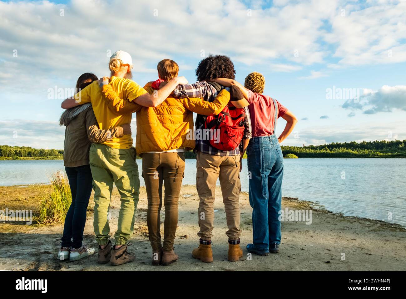 Fernweh-Lebensstil, Rückansicht einer Gruppe junger, multirassischer Freunde, die auf der Schulter stehen und sich auf der Seite umarmen Stockfoto