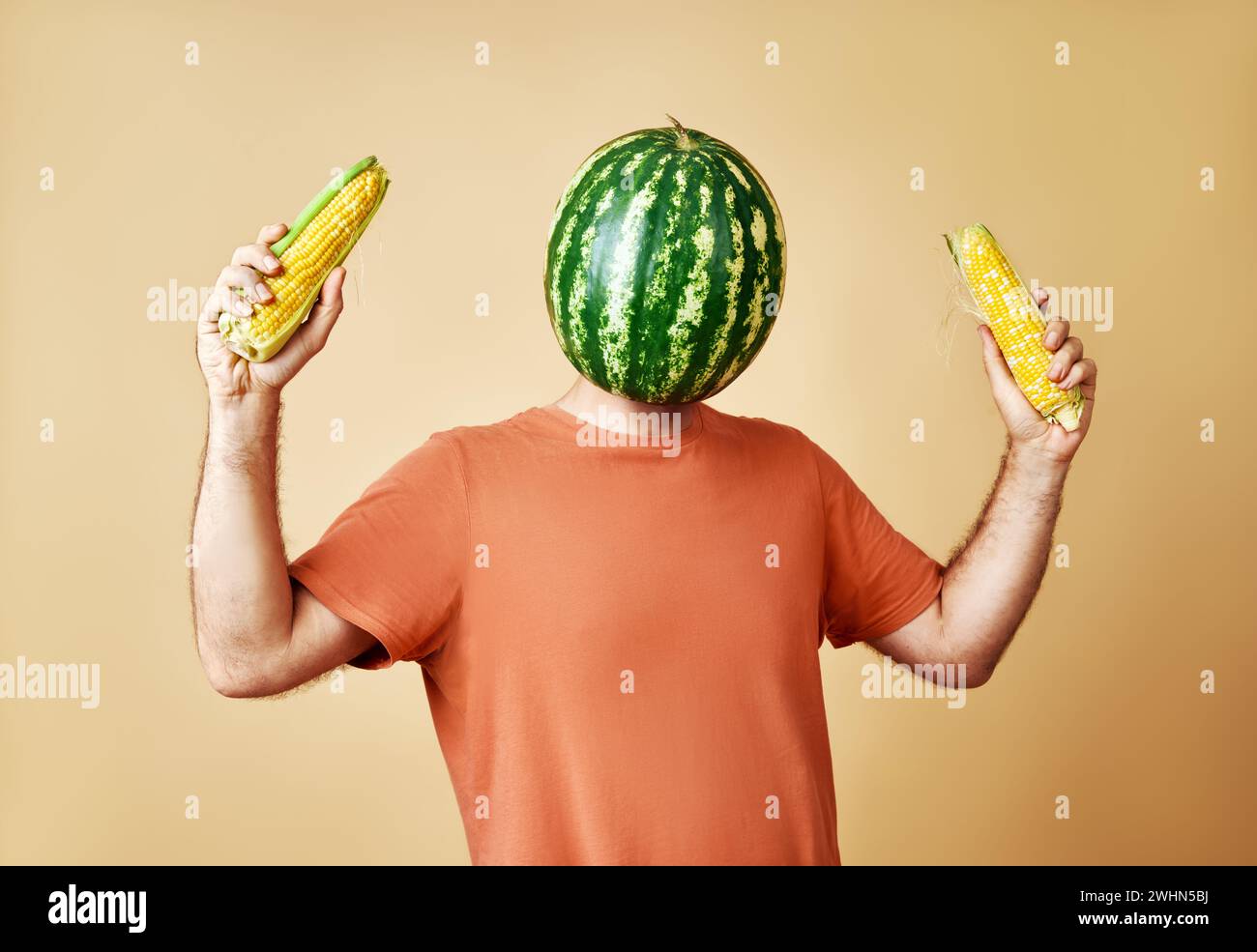 Lustiger Mann mit Wassermelone statt Kopf, der Mais hält. Konzeptuelle, zeitgenössische Kunstcollage. Stockfoto