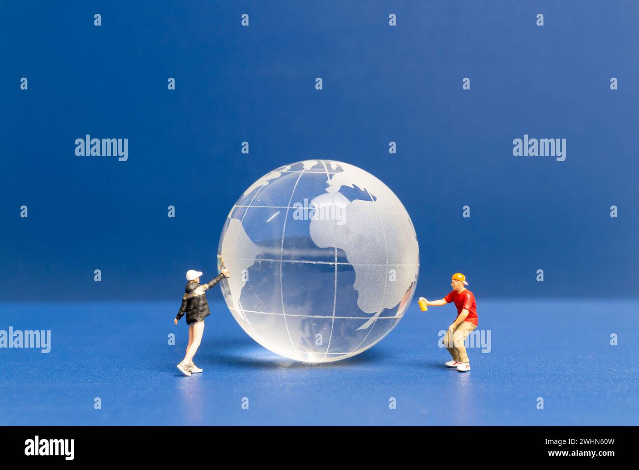 Miniaturmenschen Teenager, der Farbe Krytalkugel auf blauem Hintergrund sprüht Stockfoto