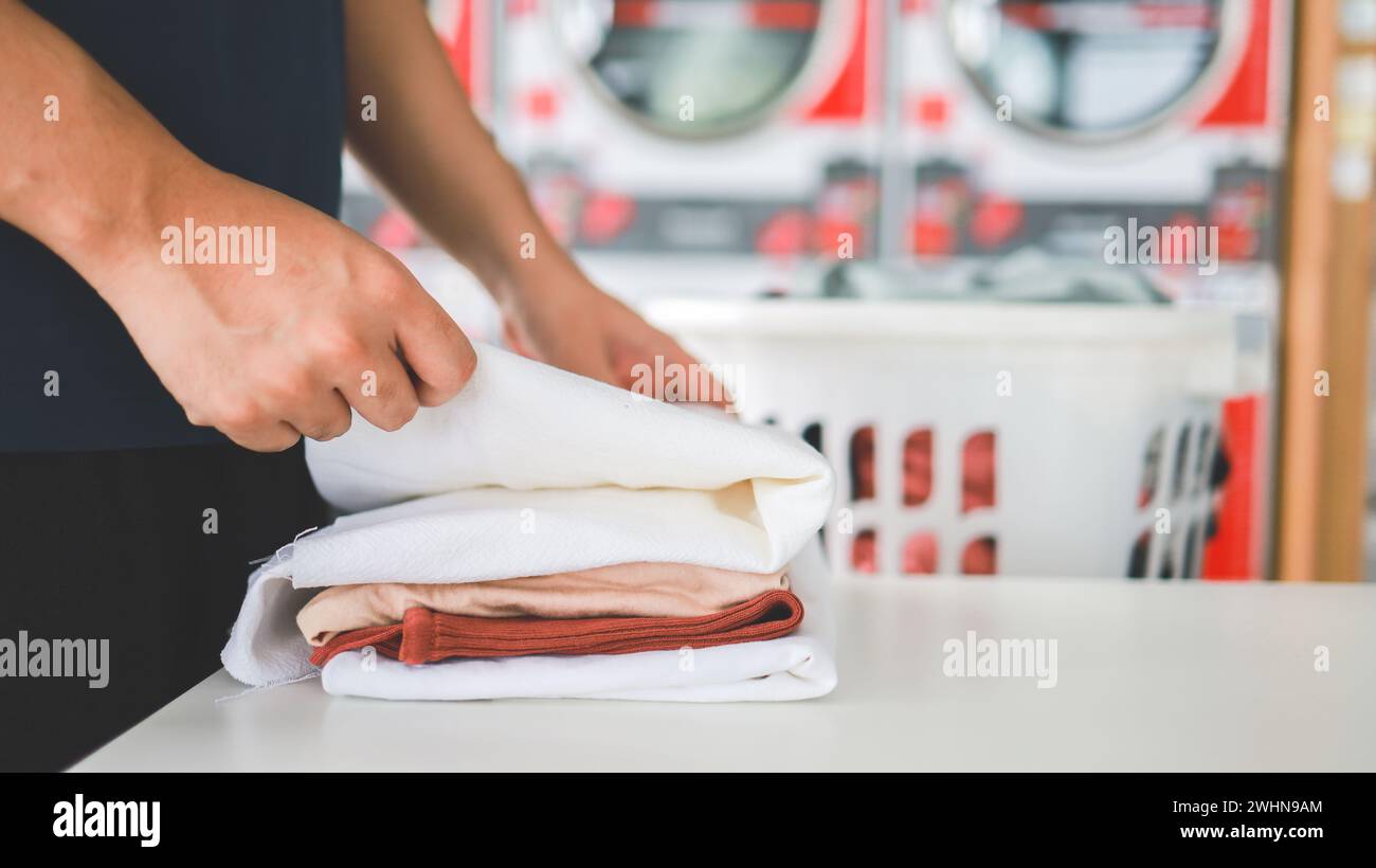 Mann, der einen Waschkorb mit schmutziger Wäsche der Waschmaschine im öffentlichen Geschäft hält. Wäschekleidung Konzept Stockfoto