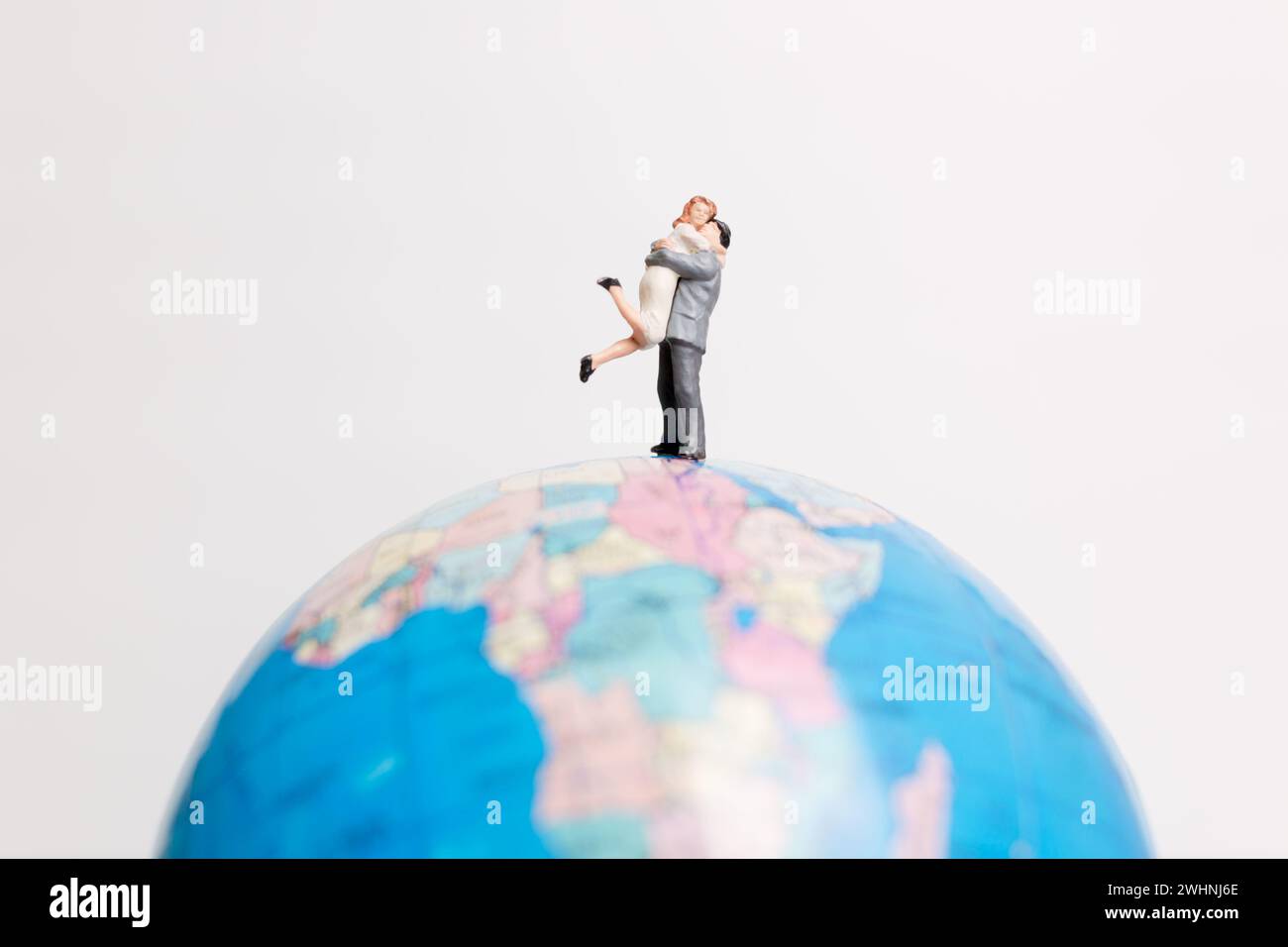 Miniaturmenschen stehen auf der Weltkarte des Globus Stockfoto
