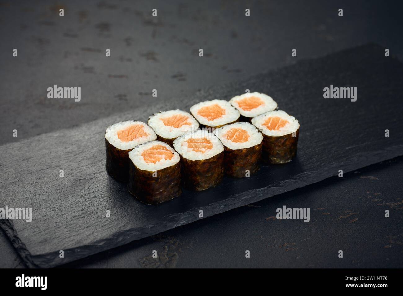 Rolle mit Lachs auf dunklem Hintergrund. Sushi-Menü. Japanisches Essen. Stockfoto
