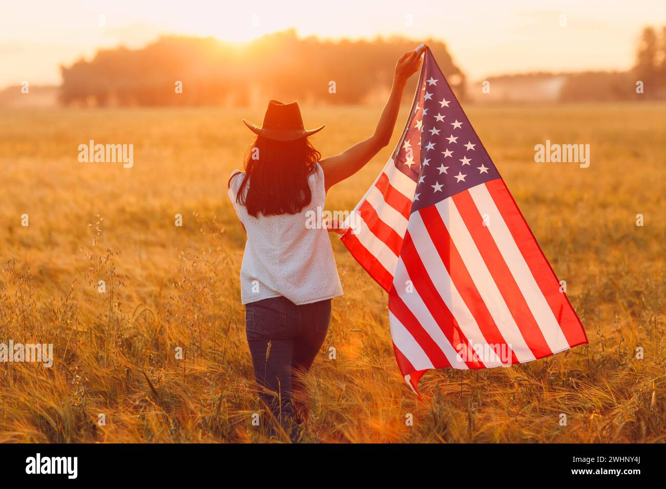 Patriotischer Unabhängigkeitstag 4. Juli Farmerin auf dem Ackerfeld mit amerikanischer Flagge bei Sonnenuntergang Stockfoto