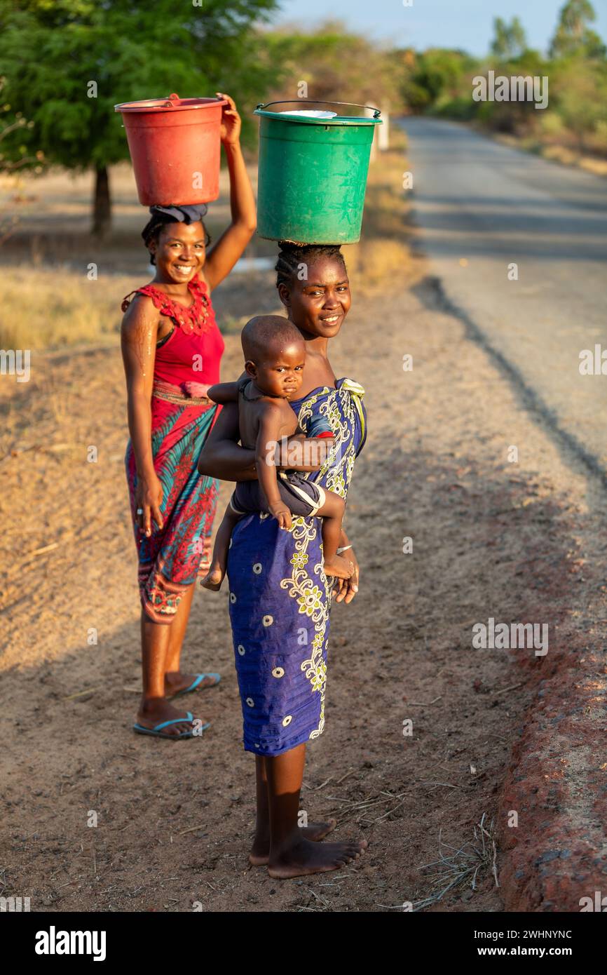 Frau mit Baby in der Hand und Container auf dem Kopf, ein häufiger Anblick in diesem ländlichen äthiopischen Dorf Stockfoto