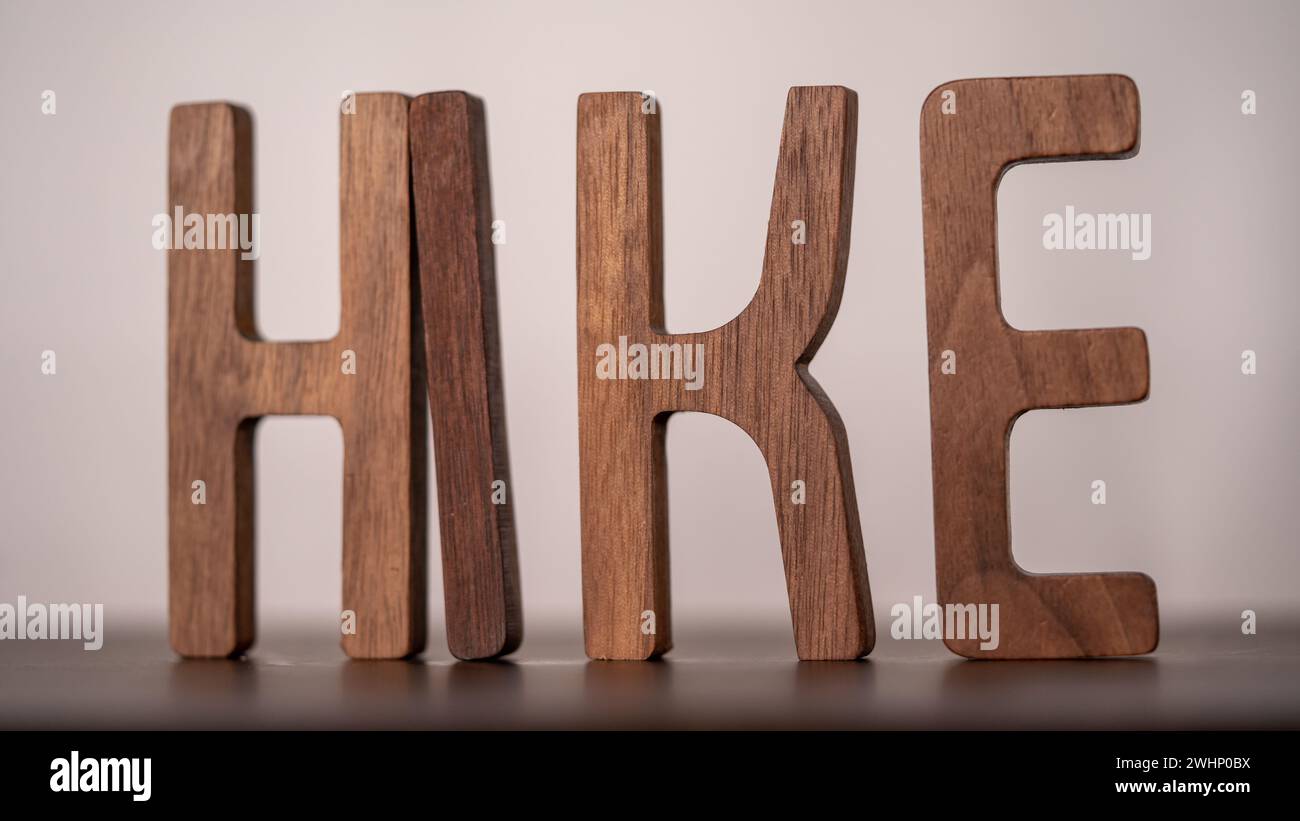 Hölzerne Buchstaben, die das Wort „WANDERUNG“ auf einem Holztisch schreiben. Stockfoto
