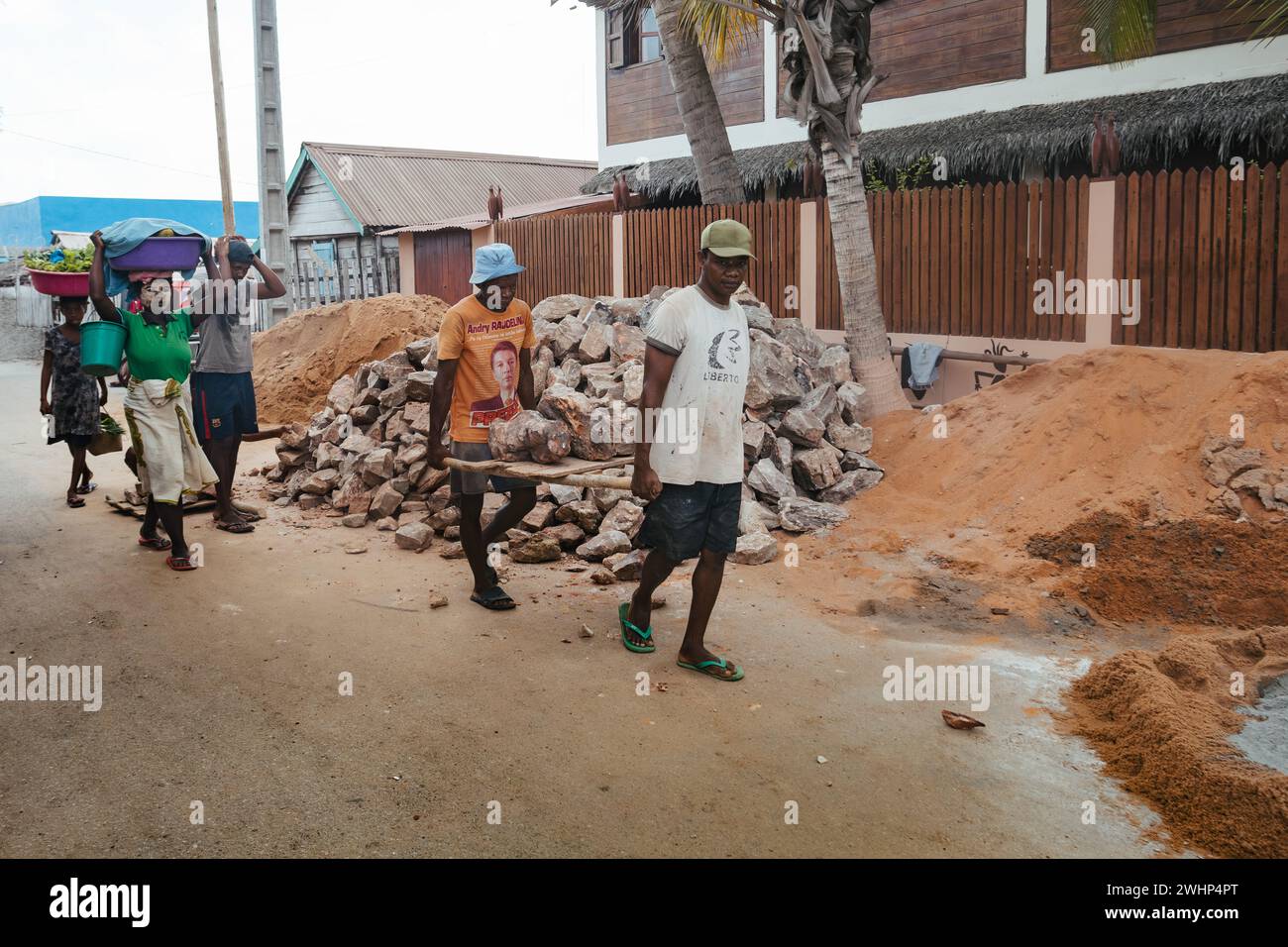 Madagassische Männer arbeiten hart, tragen Bausteine manuell. Morondava, Madagaskar Stockfoto