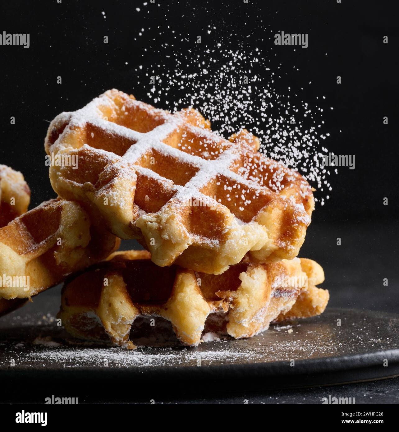 Ein Stapel gebackener belgischer Waffeln, bestreut mit Puderzucker Stockfoto