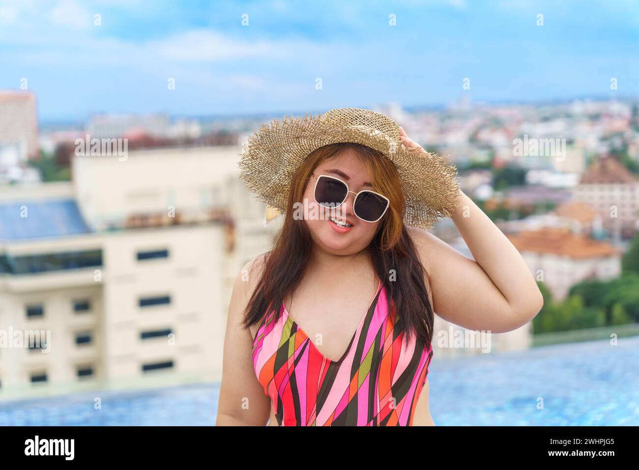 Übergewichtige junge asiatische Frau trägt orange swimsuitÂ und Strohsonnenhut am Strand entspannend im Pool glückliche und große Frau fröhlich Funn Stockfoto