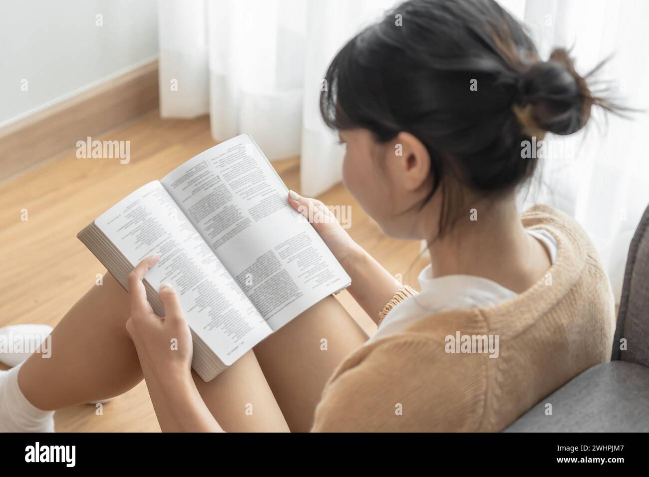 Asiatische Frauen lesen Buch und entspannen zu Hause und bequem vor dem geöffneten Buch Stockfoto