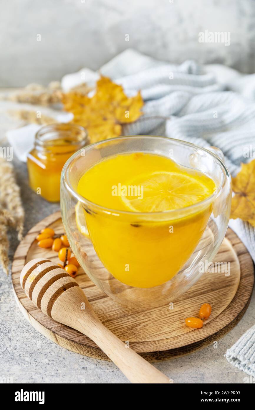 Heißer Kräuter-Vitamin-Sanddorn-Tee in einer Glasschale mit frischen Sanddorn-Beeren, Honig und Zitrone auf einer Steinplatte. Entspannen Sie Sich Stockfoto
