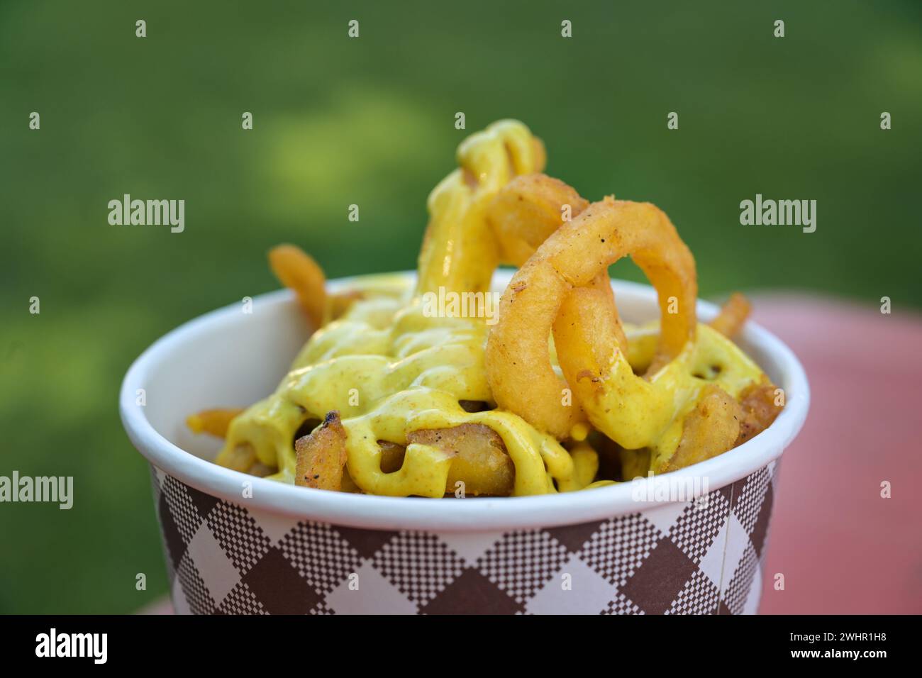 Pappschüssel mit frittierten Spiralkartoffeln und Currysauce in einem Imbissstand bei einem Outdoor-Festival, Kopierraum, ausgewählter Fokus Stockfoto