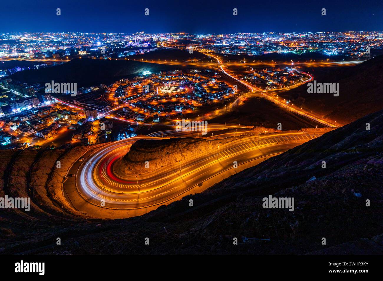 Blick vom Aussichtspunkt Amirat auf der wellenförmigen Straße in Muscat bei Nacht Stockfoto